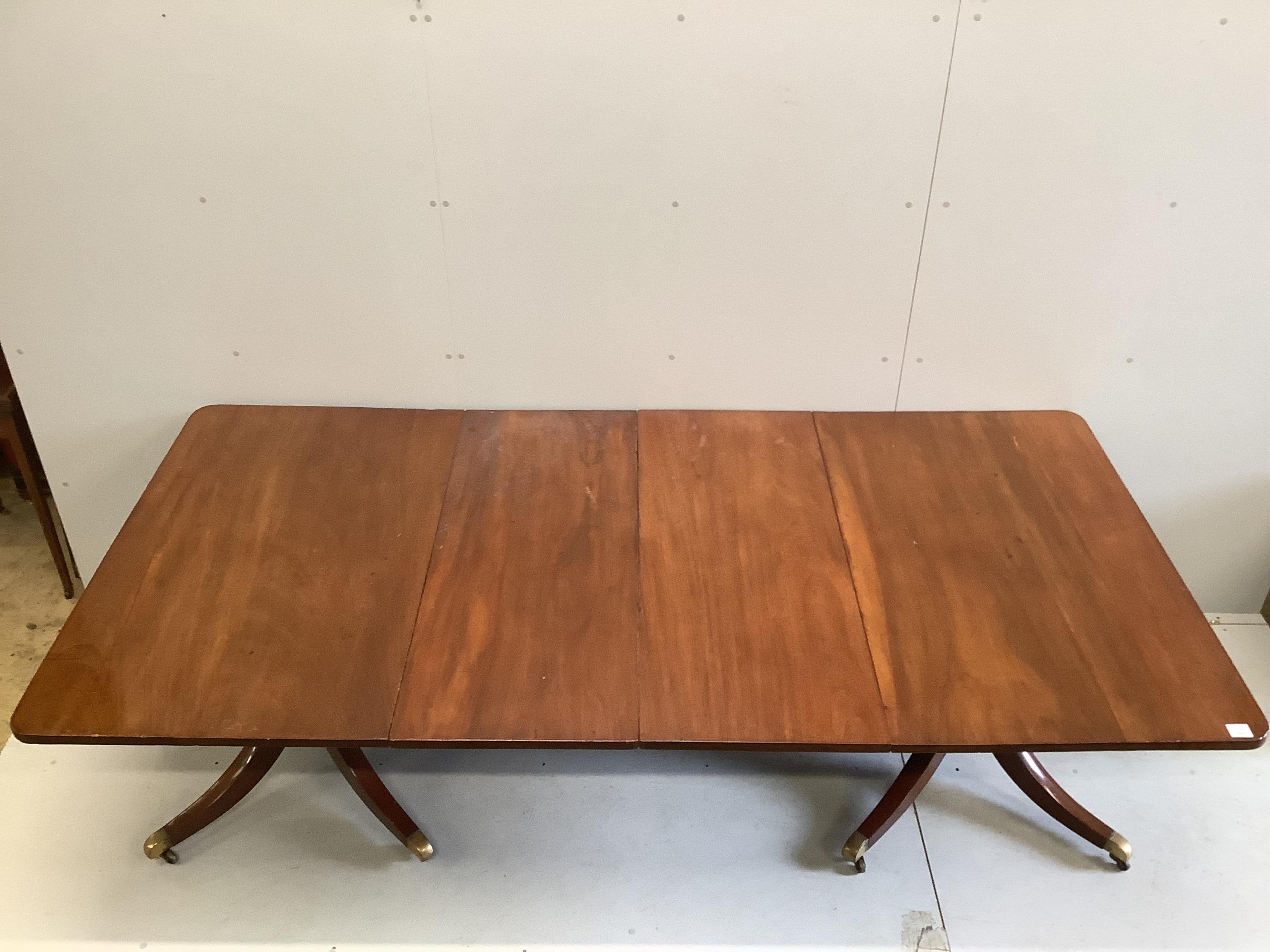 A Regency mahogany twin pillar extending dining table, width approximately 240cm extended, two spare leaves, depth 120cm, height 72cm. Condition - fair